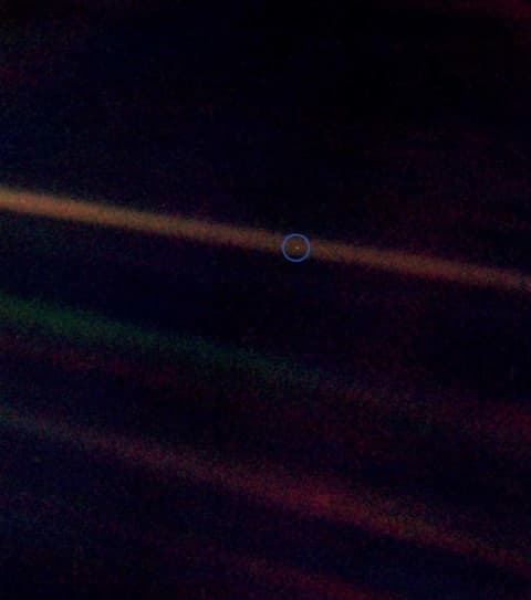 The famous "Pale Blue Dot" photo taken from Voyager 1, where Earth appears as nothing but a speck against a backdrop of the vastness of space.