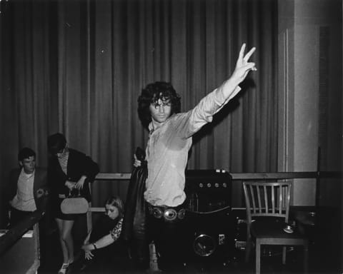 A messy-haired Morrison flashes a peace sign in 1968.