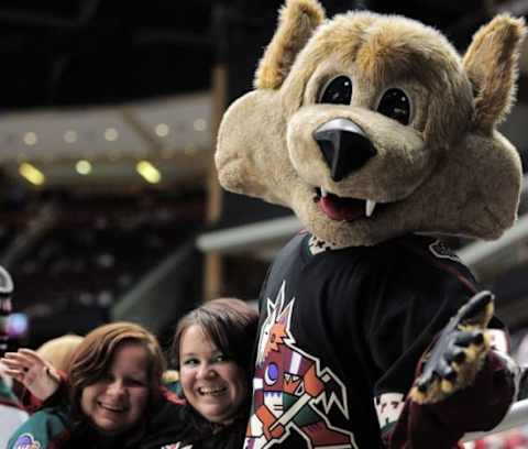 Mar 5, 2015; Glendale, AZ, USA; Arizona Coyotes mascot Howler poses with fans wearing retro uniforms before facing the Vancouver Canucks at Gila River Arena. Mandatory Credit: Joe Camporeale-USA TODAY Sports