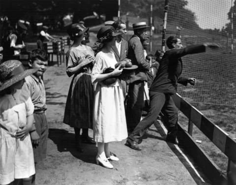 Revelers try to knock down coconuts during this "coconut shy" game at a London fair in 1922.