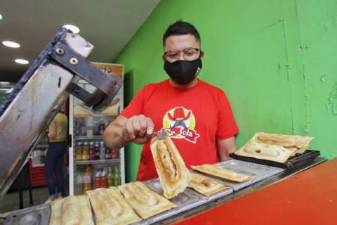 A person prepares a Panchuker hot dog.