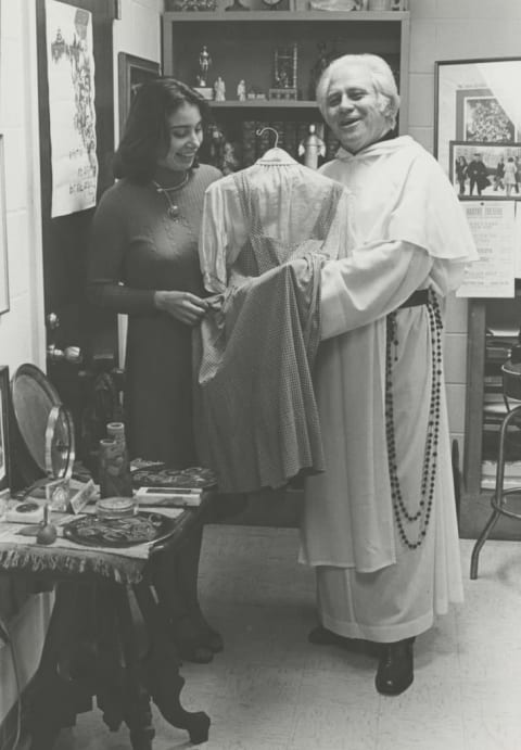 Reverend Gilbert Hartke and student Carol Pearson with the dress in the mid-1970s.