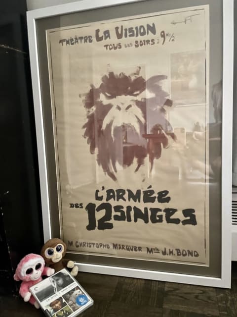 J.H. Bond's L'Armée des 12 Singes play poster from 12 Monkeys, alongside two plush monkeys and a Blu-ray of La Jetée .