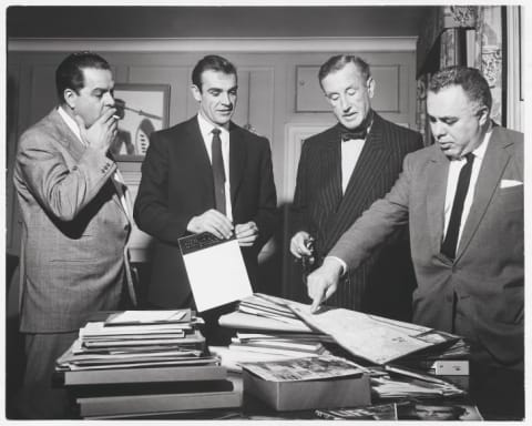 Cubby Broccoli, Sean Connery, Ian Fleming, and Harry Saltzman look at a map of Jamaica ahead of production on Dr. No (1962).