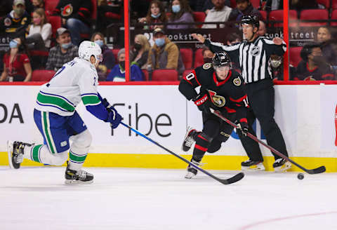 OTTAWA, ONTARIO – DECEMBER 01: Alex Formenton #10 of the Ottawa Senators skates with the puck as Luke Schenn #2 of the Vancouver Canucks pursues the play during the second period at Canadian Tire Centre on December 01, 2021 in Ottawa, Ontario. (Photo by Chris Tanouye/Getty Images)