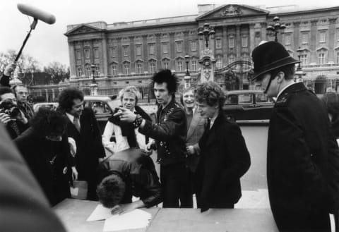 The Sex Pistols and their manager Malcolm McLaren signing a new contract with A&M Records, after being dropped from EMI, outside Buckingham Palace in 1977.