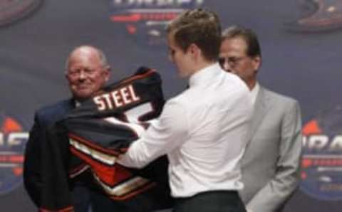 Jun 24, 2016; Buffalo, NY, USA; Sam Steel puts on a team jersey after being selected as the number thirty overall draft pick by the Anaheim Ducks in the first round of the 2016 NHL Draft at the First Niagra Center. Mandatory Credit: Timothy T. Ludwig-USA TODAY Sports