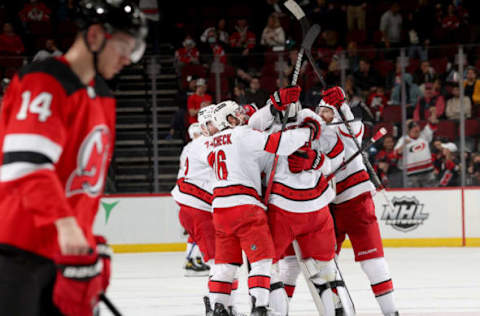 NEWARK, NEW JERSEY – APRIL 23: Pyotr Kochetkov #52 of the Carolina Hurricanes celebrates with teammates after the win as Nathan Bastian #14 of the New Jersey Devils skates off the ice at Prudential Center on April 23, 2022, in Newark, New Jersey. The Carolina Hurricanes defeated the New Jersey Devils 3-2 in overtime. Pyotr Kochetkov made his NHL debut in today’s game. (Photo by Elsa/Getty Images)