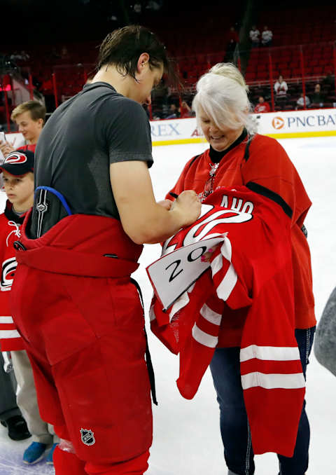 The Carolina Hurricanes’ Sebastian Aho gives his jersey to fan Sherry Hollcraft, right, at the end of a game against the New York Islanders at PNC Arena in Raleigh, N.C., on Thursday, April 6, 2017. It is a Hurricanes tradition where the team gives the shirts off their backs to lucky fans at one of the last games of the season. (Chris Seward/Raleigh News)