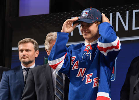 DALLAS, TX – JUNE 22: Vitali Kravtsov puts on a hat onstage after being selected ninth overall by the New York Rangers during the first round of the 2018 NHL Draft at American Airlines Center on June 22, 2018 in Dallas, Texas. (Photo by Brian Babineau/NHLI via Getty Images)