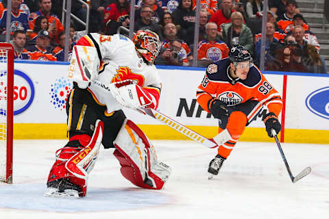 EDMONTON, AB – JANUARY 19: Calgary Flames Goalie David Rittich (33) shoots the puck out of the zone as Edmonton Oilers Right Wing Jesse Puljujarvi (98) reaches for it in the third period during the Edmonton Oilers game versus the Calgary Flames on January 19, 2019 at Rogers Place in Edmonton, AB. (Photo by Curtis Comeau/Icon Sportswire via Getty Images)