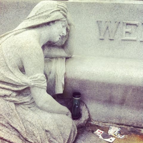 Playing cards near a statue at Houdini's grave in Queens