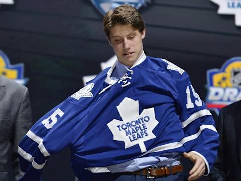 Jun 26, 2015; Sunrise, FL, USA; Mitchell Marner puts on a team jersey after being selected as the number four overall pick to the Toronto Maple Leafs in the first round of the 2015 NHL Draft at BB&T Center. Mandatory Credit: Steve Mitchell-USA TODAY Sports