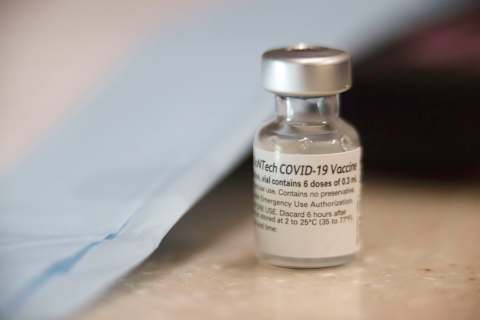 A vaccine vial sits next to PPE. (Photo by Stephen Zenner/SOPA Images/LightRocket via Getty Images)