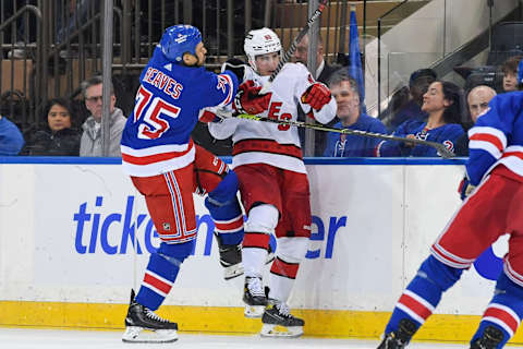 New York Rangers right wing Ryan Reaves (75) checks Carolina Hurricanes center Martin Necas (88) into the boards (Credit: Dennis Schneidler-USA TODAY Sports)