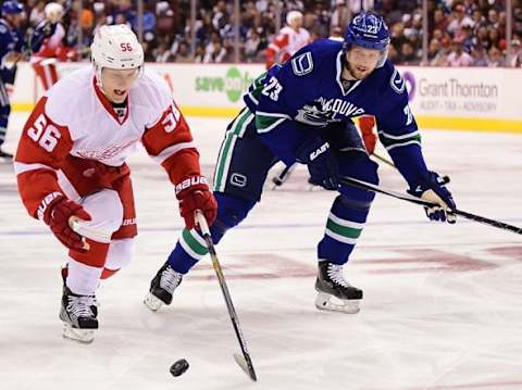 Oct 24, 2015; Vancouver, British Columbia, CAN; Detroit Red Wings forward Teemu Pulkkinen (56) reaches for the puck against Vancouver Canucks defenseman Alexander Edler (23) during the first period at Rogers Arena. Mandatory Credit: Anne-Marie Sorvin-USA TODAY Sports