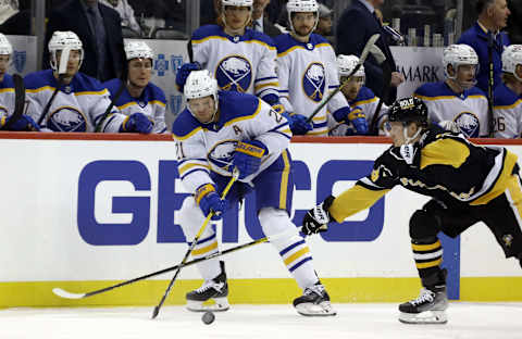 Dec 17, 2021; Pittsburgh, Pennsylvania, USA; Buffalo Sabres right wing Kyle Okposo (21) moves the puck against Pittsburgh Penguins left wing Danton Heinen (43) during the first period at PPG Paints Arena. Mandatory Credit: Charles LeClaire-USA TODAY Sports