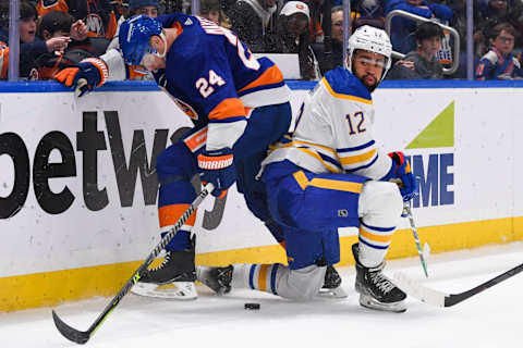 Mar 7, 2023; Elmont, New York, USA; New York Islanders defenseman Scott Mayfield (24) and Buffalo Sabres left wing Jordan Greenway (12) battle for loose puck during the third period at UBS Arena. Mandatory Credit: Dennis Schneidler-USA TODAY Sports