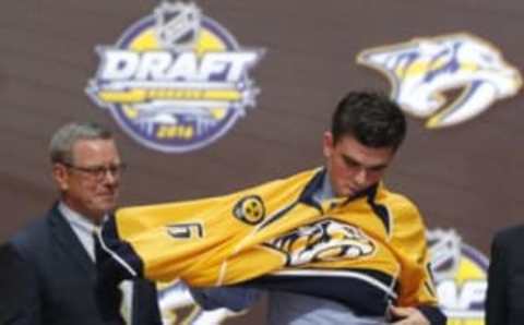 Jun 24, 2016; Buffalo, NY, USA; Dante Fabbro puts on a team jersey after being selected as the number seventeen overall draft pick by the Nashville Predators in the first round of the 2016 NHL Draft at the First Niagra Center. Mandatory Credit: Timothy T. Ludwig-USA TODAY Sports