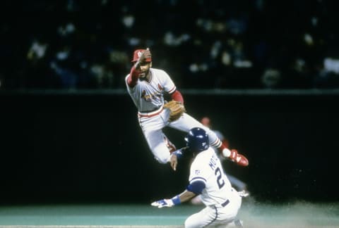 KANSAS CIT, MO – OCTOBER 1985: Shortstop Ozzie Smith #1 of the St. Louis Cardinals avoids the slide of Darryl Motley #24 of the Kansas City Royals to get his throw off to first base during the World Series in October 1985 at Royals Stadium in Kansas City, Missouri. The Royals won the World Series 4 games to 3. Smith played for the Cardinals from 1982-96. (Photo by Focus on Sport/Getty Images)