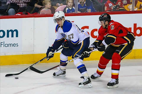 Mar 24, 2013; Calgary, Alberta, CAN; St. Louis Blues forward David Perron (57) and Calgary Flames defenseman Wade Redden (6) fight for the puck during the first period at the Scotiabank Saddledome. Calgary Flames won 3-2. Mandatory Credit: Sergei Belski-USA TODAY Sports