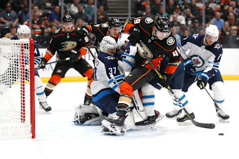 ANAHEIM, CALIFORNIA – OCTOBER 29: Connor Hellebuyck #37 of the Winnipeg Jets defends against Max Jones #49 of the Anaheim Ducks during the first period of a game at Honda Center on October 29, 2019 in Anaheim, California. (Photo by Sean M. Haffey/Getty Images)