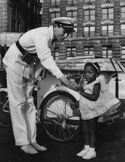 An ice cream vendor in New York hands a young girl an ice cream, circa 1920.