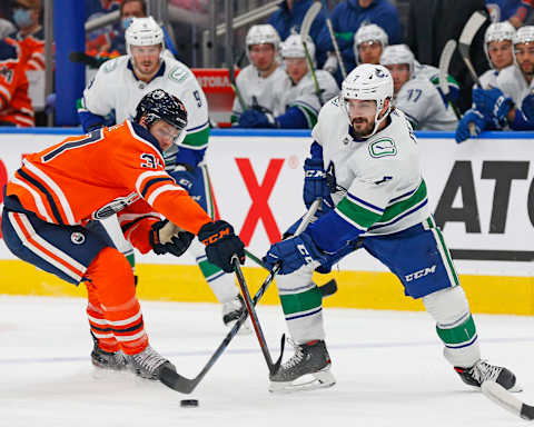 Oct 7, 2021; Edmonton, Alberta, CAN; Vancouver Canucks forward Nic Petan (7) and Edmonton Oilers forward Warren Foegele (37) battle for a loose puck during the second period at Rogers Place. Mandatory Credit: Perry Nelson-USA TODAY Sports