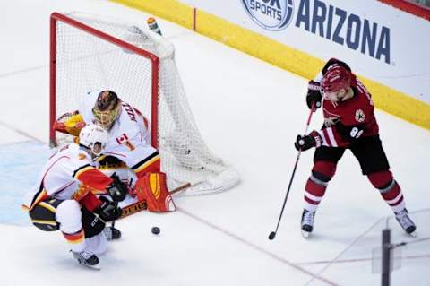 Feb 12, 2016; Glendale, AZ, USA; Arizona Coyotes left wing Mikkel Boedker (89) shoots the puck as Calgary Flames goalie Jonas Hiller (1) and defenseman T.J. Brodie (7) defend during the third period at Gila River Arena. Mandatory Credit: Matt Kartozian-USA TODAY Sports