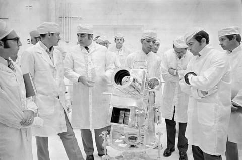 George Carruthers surrounded by other scientists looking at the Lunar Surface Ultraviolet Camera.