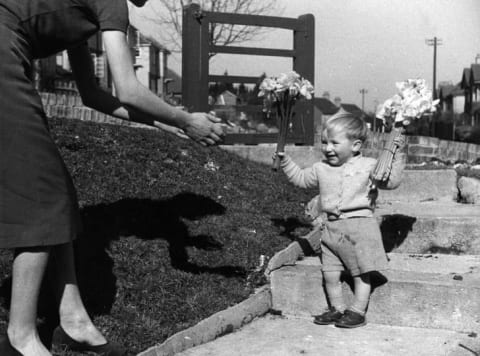 A little boy gives his mother some flowers