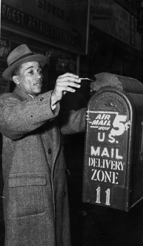 A man mailing a letter in 1960s New York.