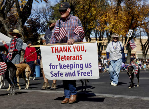 elderly man at a parade with a sign thanking veterans