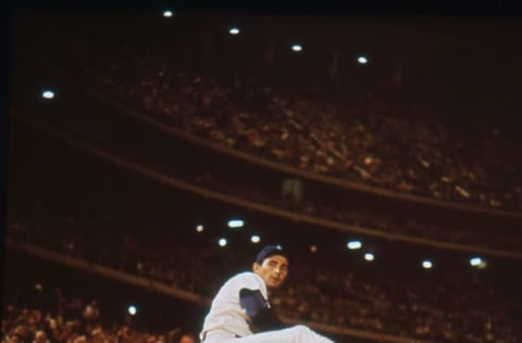 American baseball player Sandy Koufax, of the Los Angeles Dodgers, winds up a pitch on the sidelines in a crowded stadium, circa 1965. (Photo by PhotoQuest/Getty Images)