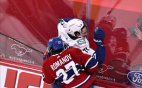 Mar 19, 2021; Montreal, Quebec, CAN; Vancouver Canucks center Zack MacEwen (71) is checked into the boards by Montreal Canadiens left wing Alexander Romanov (27) during the first period at Bell Centre. Mandatory Credit: Jean-Yves Ahern-USA TODAY Sports