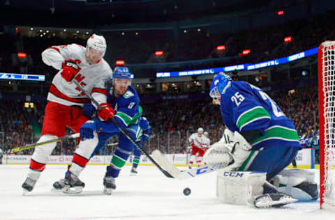 VANCOUVER, BC – DECEMBER 12: Christopher Tanev #8 of the Vancouver Canucks looks on as teammate Jacob Markstrom #25 makes a save against Warren Foegele #13 of the Carolina Hurricanes during their NHL game at Rogers Arena December 12, 2019 in Vancouver, British Columbia, Canada. Vancouver won 1-0. (Photo by Jeff Vinnick/NHLI via Getty Images)