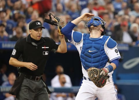 TORONTO, ON – AUGUST 20: Danny Janssen #9 of the Toronto Blue Jays takes his mask off as he prepares to catch a foul pop up in the third inning as home plate umpire Adam Hamari #78 watches during MLB game action against the Baltimore Orioles at Rogers Centre on August 20, 2018 in Toronto, Canada. (Photo by Tom Szczerbowski/Getty Images)