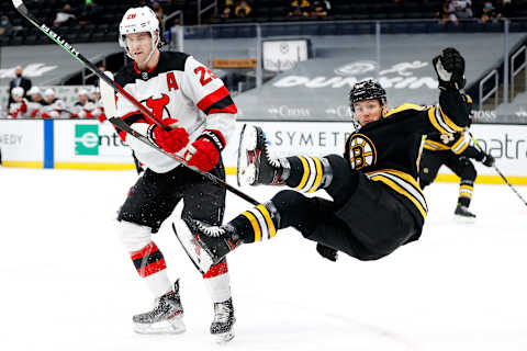 BOSTON, MASSACHUSETTS – MARCH 30: Jeremy Lauzon #55 of the Boston Bruins falls over Damon Severson #28 of the New Jersey Devils . (Photo by Maddie Meyer/Getty Images)