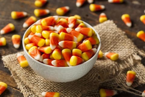 A bowl of candy corn on a piece of burlap.