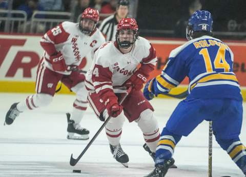 Wisconsin defenseman Corson Ceulemans (4) has possession of the hockey puck while Lake Superior State forward Brett Roloson (14) plays defense during the Kwik Trip Face-Off Tournament Wednesday, Dec. 28, 2022, at Fiserv Forum in Milwaukee.Mjs 12282022 Uwhockey28 Ec019374 1