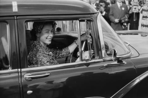 Queen Elizabeth II drives a car in 1958.