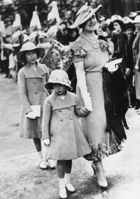 Queen consort Elizabeth holds Princess Margaret's hand as Princess Elizabeth follows, in 1936.