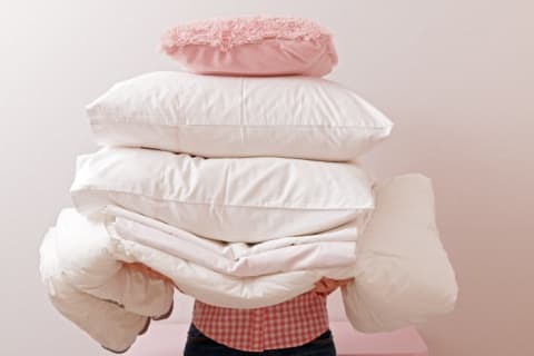 person carrying a pile of pillows