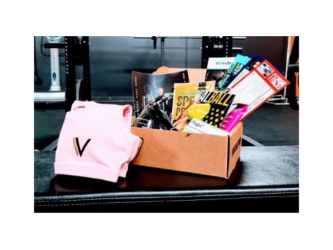 A subscription box filled with goods on a weight bench in a gym