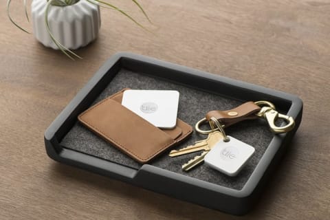 Tile trackers sitting in a tray inside a wallet and attached to a keychain.