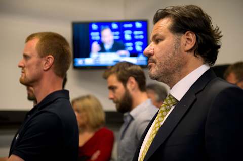 VANCOUVER, CANADA – JUNE 25: Vancouver Canucks team owner Francesco Aquilini, Henrik Sedin #33 and Chris Higgins #20 of the Vancouver Canucks listen to new head coach John Tortorella speaking during a press conference announcing Tortorella as the new head coach of the team, June 25, 2013 at Rogers Arena in Vancouver, British Columbia, Canada. (Photo by Rich Lam/Getty Images)