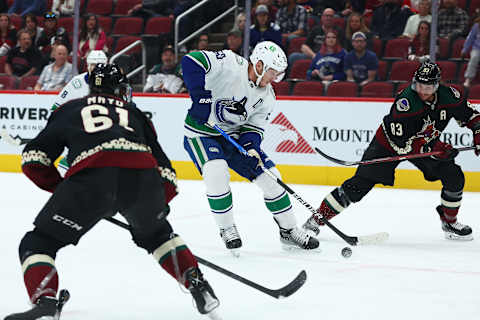 Apr 7, 2022; Glendale, Arizona, USA; Vancouver Canucks center Bo Horvat (53) moves the puck against Arizona Coyotes defenseman Dysin Mayo (61) and center Jay Beagle (83) during the first period at Gila River Arena. Mandatory Credit: Mark J. Rebilas-USA TODAY Sports