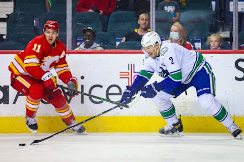 Oct 1, 2021; Calgary, Alberta, CAN; Vancouver Canucks defenseman Luke Schenn (2) and Calgary Flames center Mikael Backlund (11) battle for the puck during the first period at Scotiabank Saddledome. Mandatory Credit: Sergei Belski-USA TODAY Sports