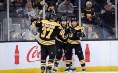 Feb 18, 2023; Boston, Massachusetts, USA; Boston Bruins left wing Jake DeBrusk (74) (middle) reacts with left wing Brad Marchand (63) and center Patrice Bergeron (37) after scoring a goal during the first period against the New York Islanders at TD Garden. Mandatory Credit: Bob DeChiara-USA TODAY Sports