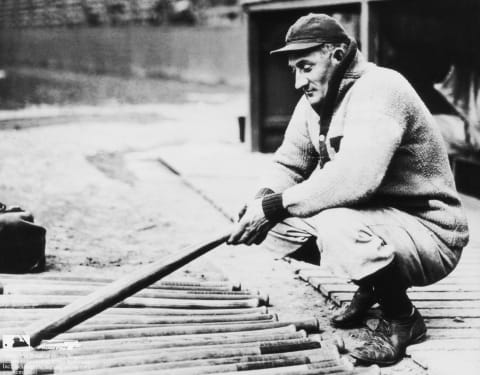 circa 1910: American baseball player Honus Wagner (1874 – 1955), aka ‘The Flying Dutchman,’ infielder, outfielder and slugger for the Pittsburgh Pirates, crouches with a baseball bat in his hand near a group of bats outside a dugout. (Photo by Photo File/Getty Images)